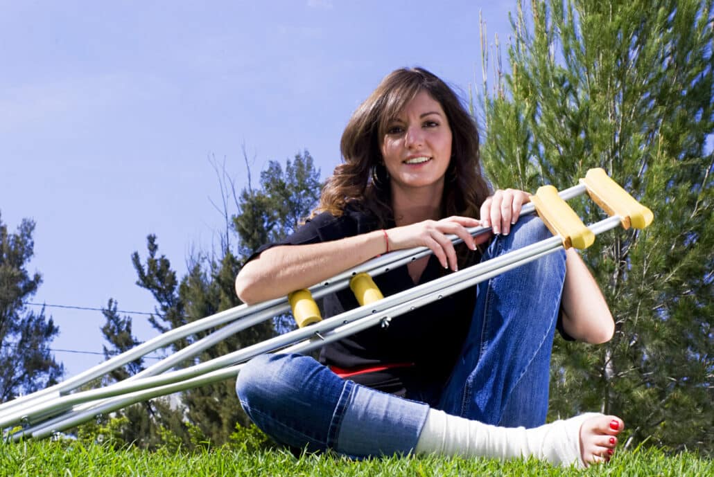 A young woman with a leg injury is using Rehab Equipment (crutches)