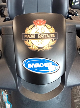 A close up of Sir Robert's Invacare scooter's insignia. The insignia reads 'NZ 26th Māori Battalion."